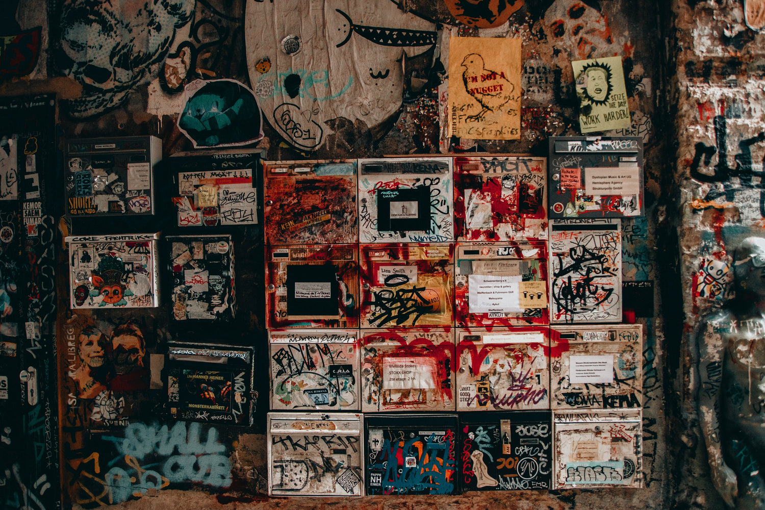 Viele vollgemalte Briefkästen in einem Hausflur in Kreuzberg.
