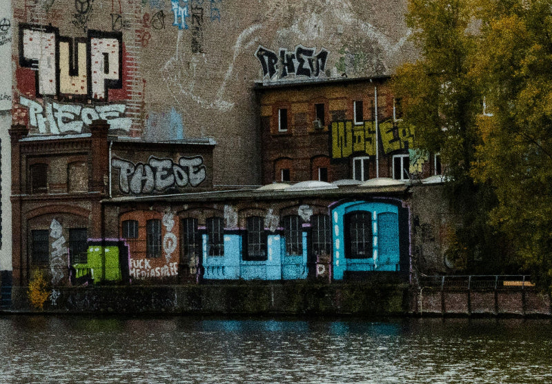 Foto von einer Hauswand vor der Spree mit einem One UP Graffiti in weiß/gelb.