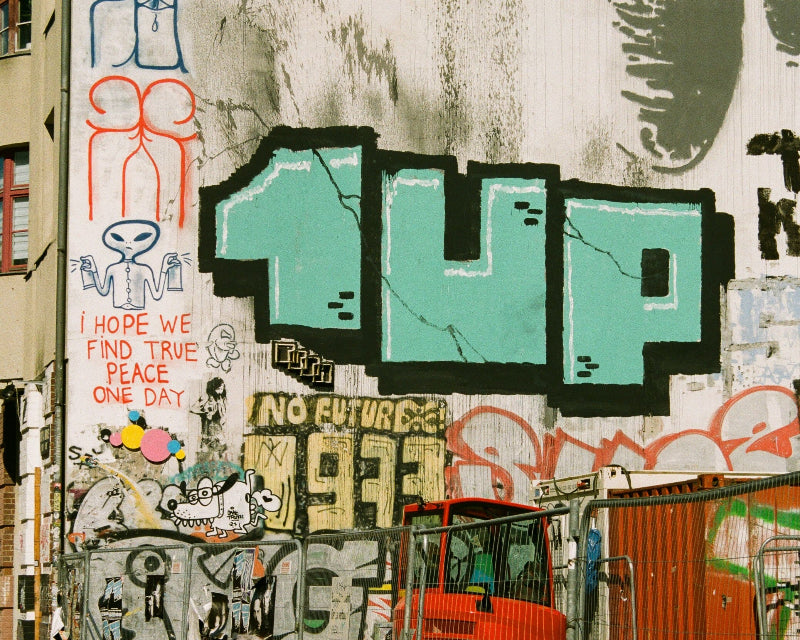 Foto von einem großen 1UP-Graffiti neben anderen Graffitis in Berlin. 
