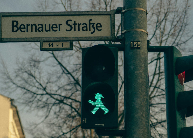 Straßenschild der Bernauer Straße und Ampel mit Ampelmännchen in grün. 