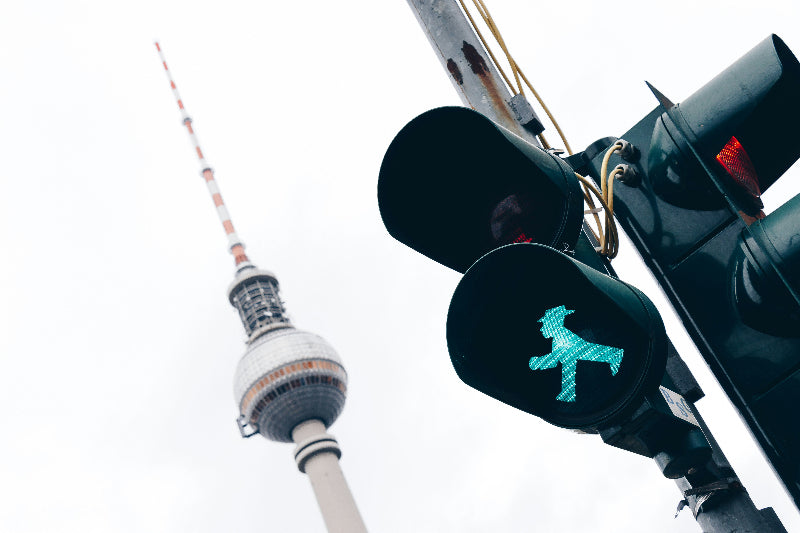 Ampel mit grünem Ampelmännchenund Fernsehturm im Hintergrund. 