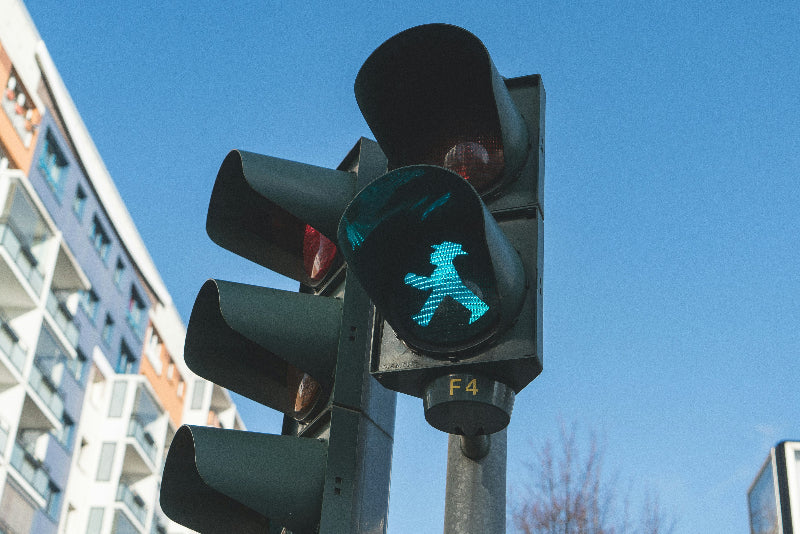 Ampel aus Berlin mit berühmten Ampelmännchen und Wohnhaus im Hintergrund. 
