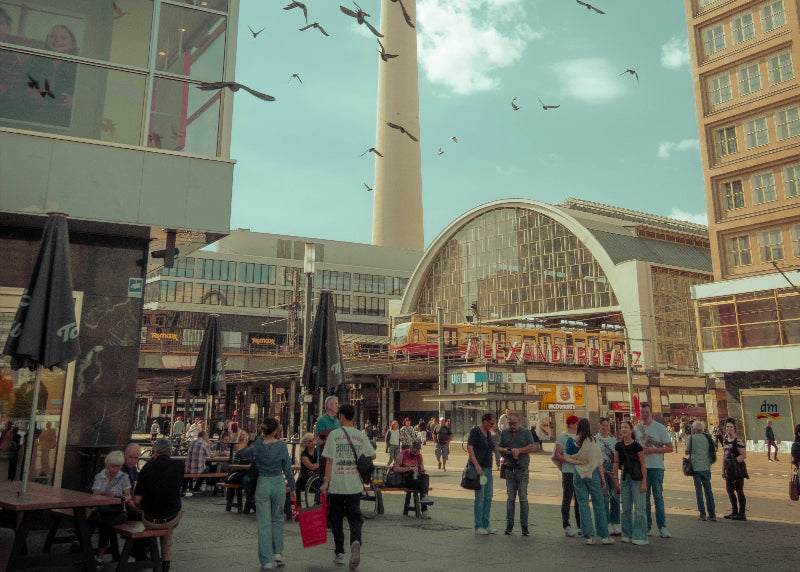Alexanderplatz mit Fernsehturm und Bahnhofshalle im Hintergrund und vielen Besuchern.