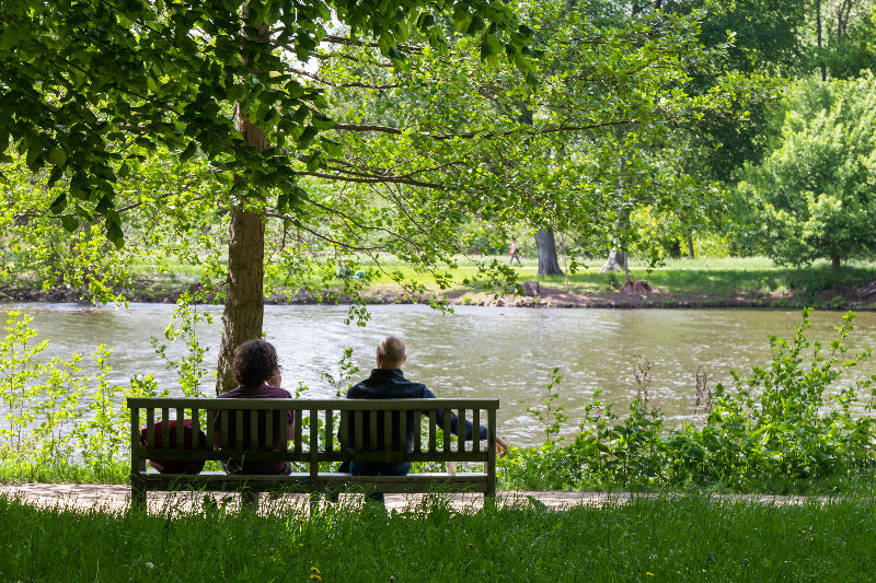 Foto von einer Bank mit 2 Menschen und Blick auf einen See in Friedrichshain. 