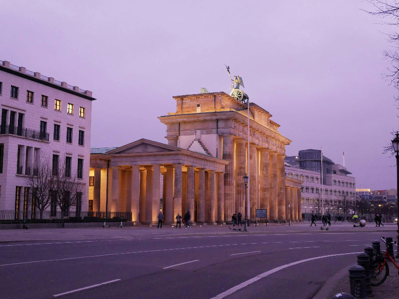 Foto vom beleuchteten Brandenburger Tor von der Seite bei Dämmerung. 