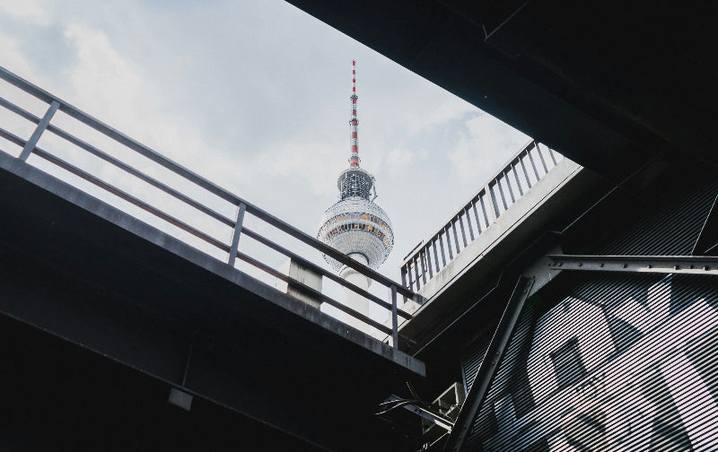 Foto mit einer dunklen Brücke und Fernsehturm im Hintergrund. 
