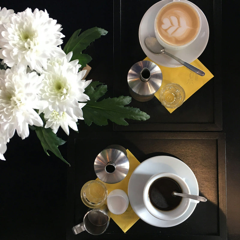 Foto von einem gedeckten Tisch mit Kaffee und Blumen. 