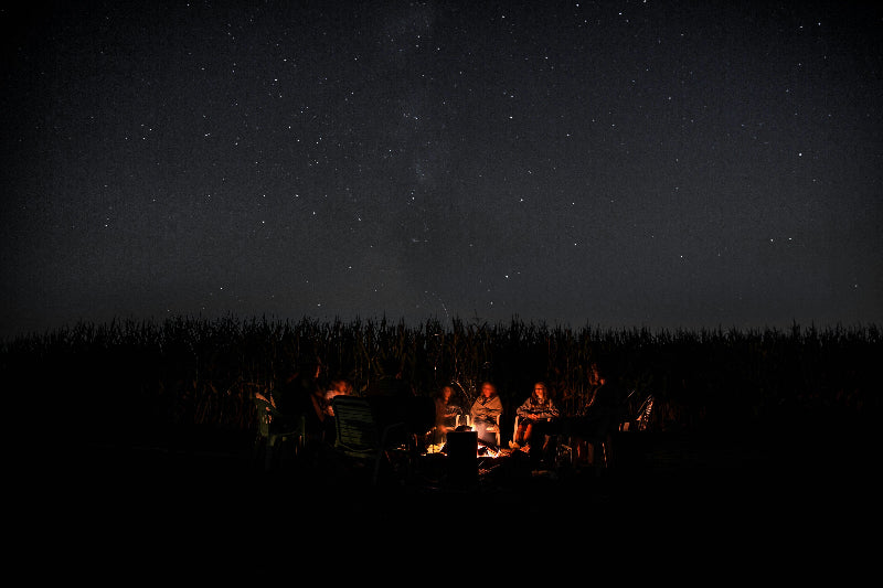 Foto von Campern an einem Lagerfeuer mit großem Sternenhimmel