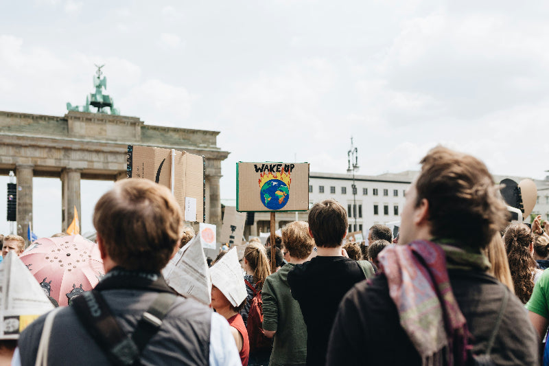 Foto von demonstrierenden mit Schildern vor dem Brandenburger Tor. 
