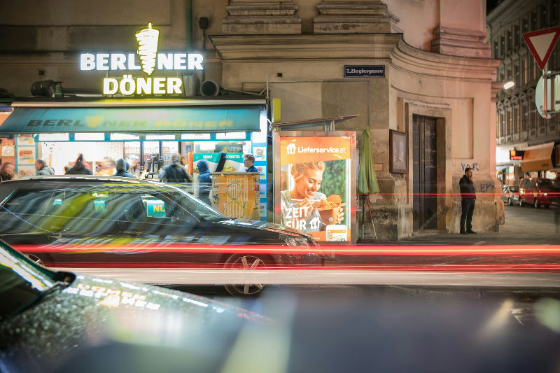 Foto von der Straße auf einen Dönerladen mit dem Namen "Berlin-Döner" mit Menschenmassen davor. 