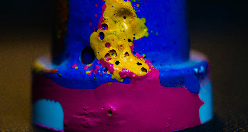 verschiedene Farbklekse in gelb, blau und rot auf Metall. 