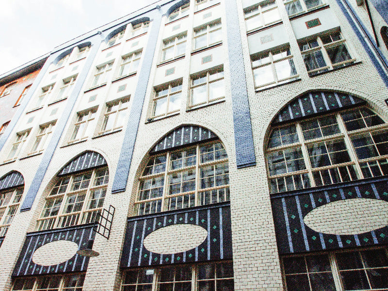 Berliner Altbau-Fassade in den Hackeschen Höfen in blau und grauen Steinen mit großen Fenstern. 