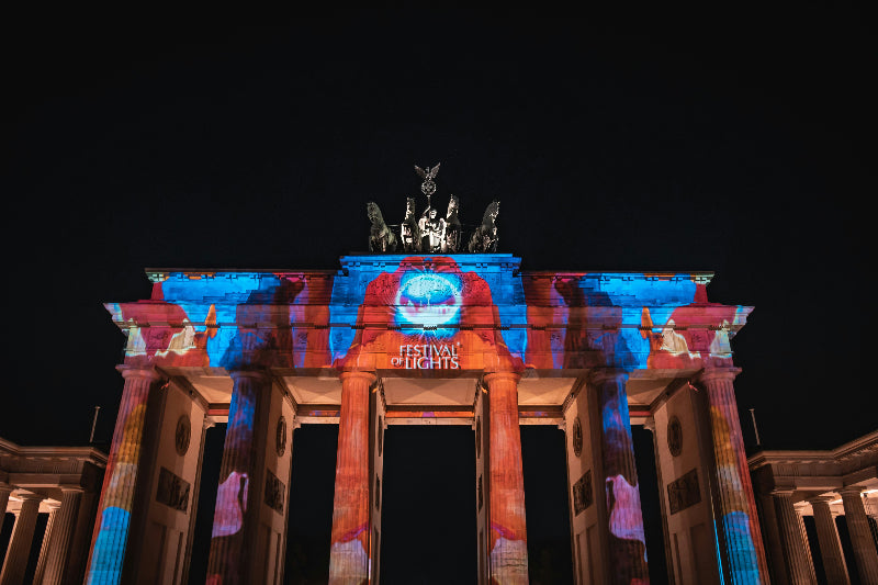 Brandenburger Tor mit Festival of Lights Logo angestrahlt bei Nacht. 