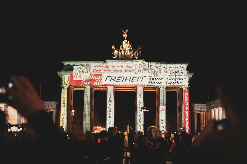 Angestrahltes Brandenburger Tor beim Festival of lights mit Menschenmassen davor. 