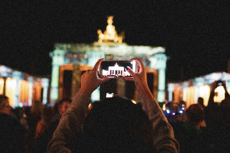 Telefon welches gerade das angestrahlte Brandenburger Tor fotografiert. 