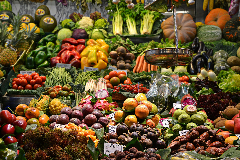 Bunte Obst und Gemüseauslage auf einem Stand in einer Markthalle. 