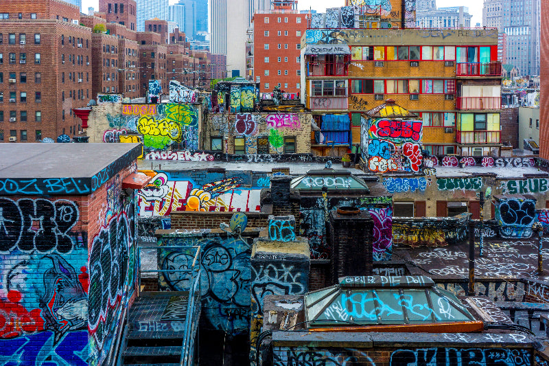 Foto von vielen Graffitis auf verschiedensten Häusern mit einer Skyline im Hintergrund. 
