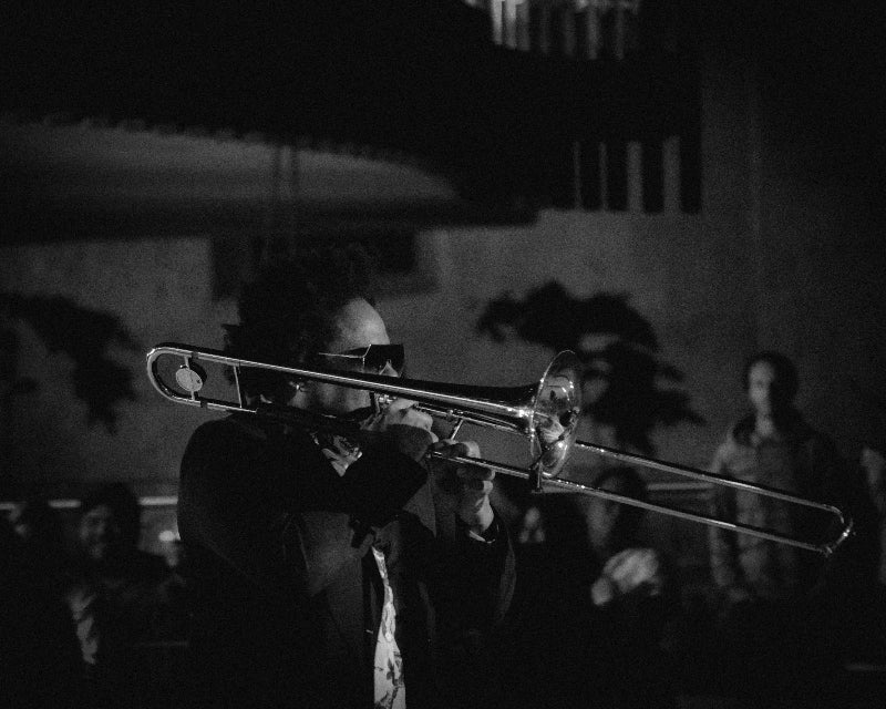 Foto eines Jazz Musikers mit Trompete und Sonnenbrille auf einer Bühne. 