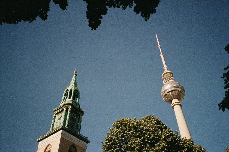 Foto von unten mit Kirche, Bäumen und Turm in Berlin. 