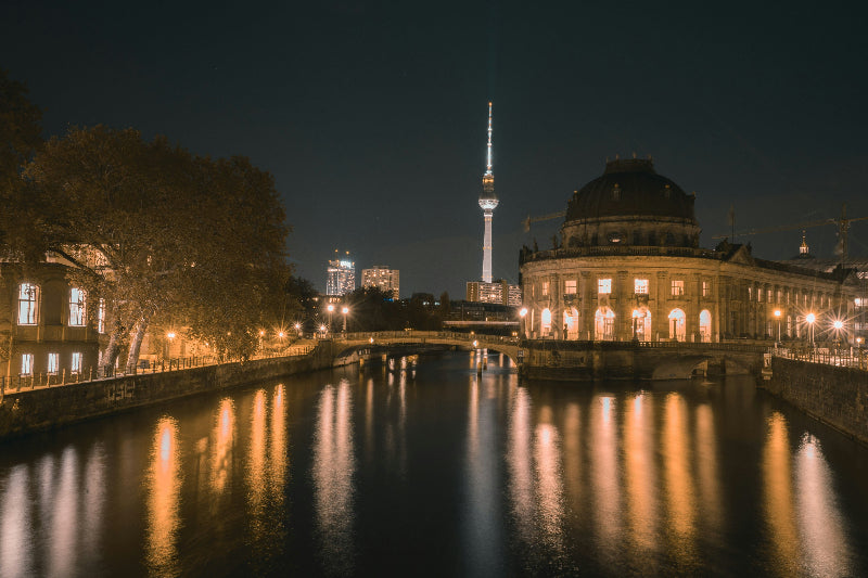 Foto von der Museumsinsel und dem Fernsehturm bei Nacht mit Spiegelung in der Spree. 