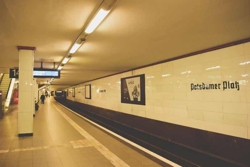 Foto der u-Bahnstation "Berlin Potsdamer Platz" mit Fahrgästen und Anzeige. 