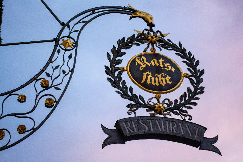 Foto von einem mit gold verziertem Schild mit der Aufschrift "Rastsstube Restaurant"