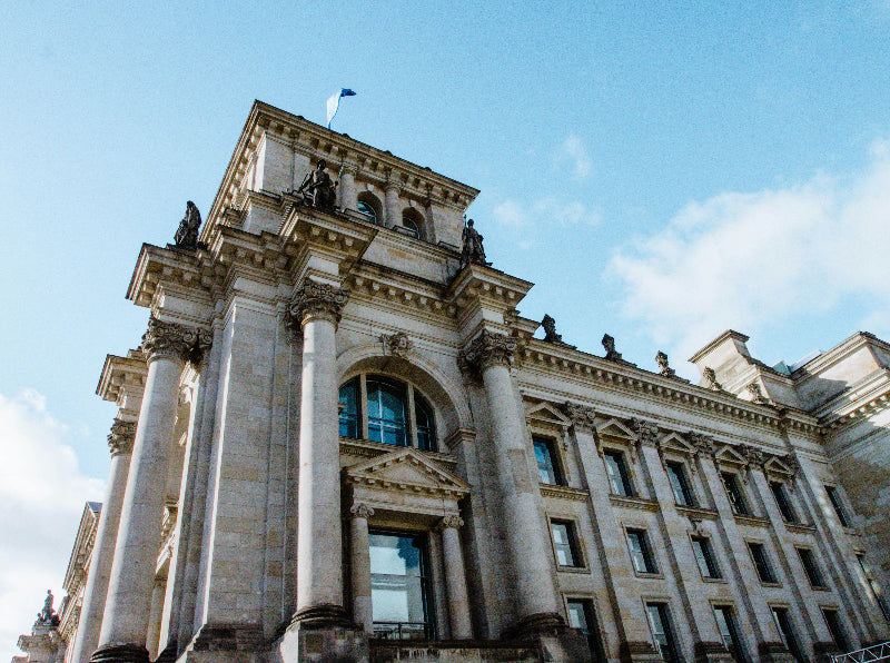 Reichstagsgebäude von unten fotografiert mit blauem Himmel und Fassade. 