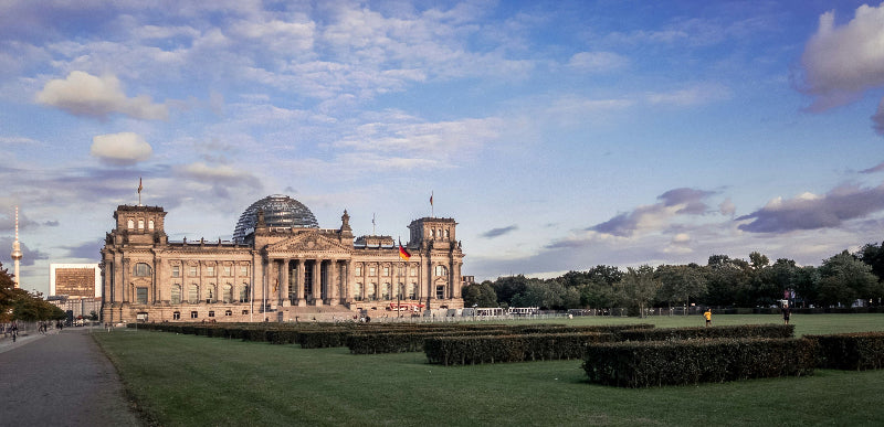 Reichstag mit Glaskuppel und deutschen Flaggen mit Vorplatz in Berlin, Deutschland. 