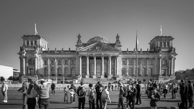 Schwarz-weiss foto vom Reichstag mit vielen Besuchern davor. 