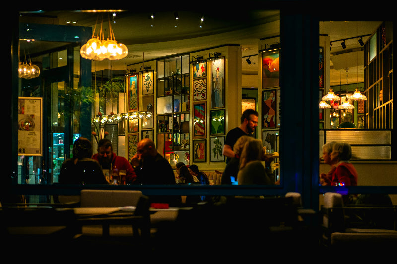 Foto von einem Berliner Restaurant in fröhlichen Farben und vielen Gästen mit Bildern an der Wand.