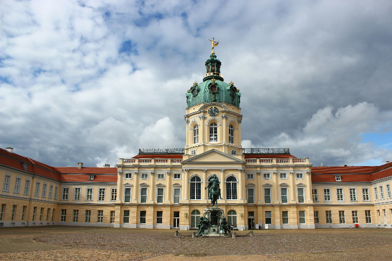 Eingang vom Schloss Charlottenburg mit Statue und bewölktem Himmel. 