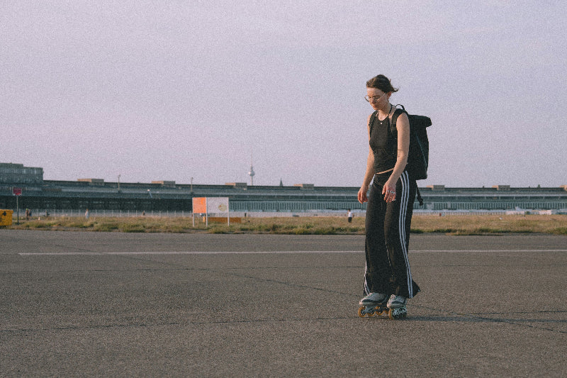 Weibliche Skaterin auf dem Tempelhofer Feld mit Flughafengelände im Hintergrund