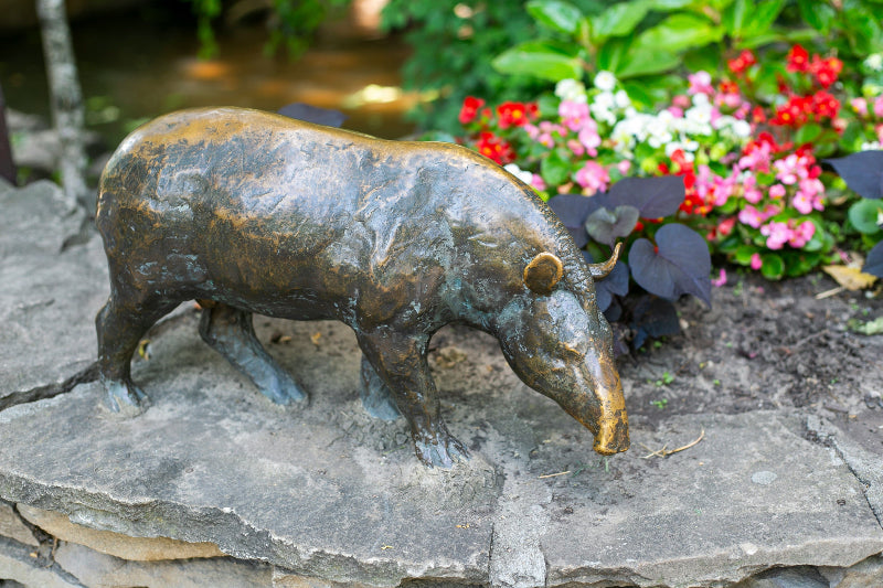 Nasenbär-Statue im Berliner Zoo, im Hintergrund Blumen.