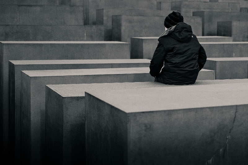 Person, welche auf den Stelen des Holocaust Mahnmal sitzt. 