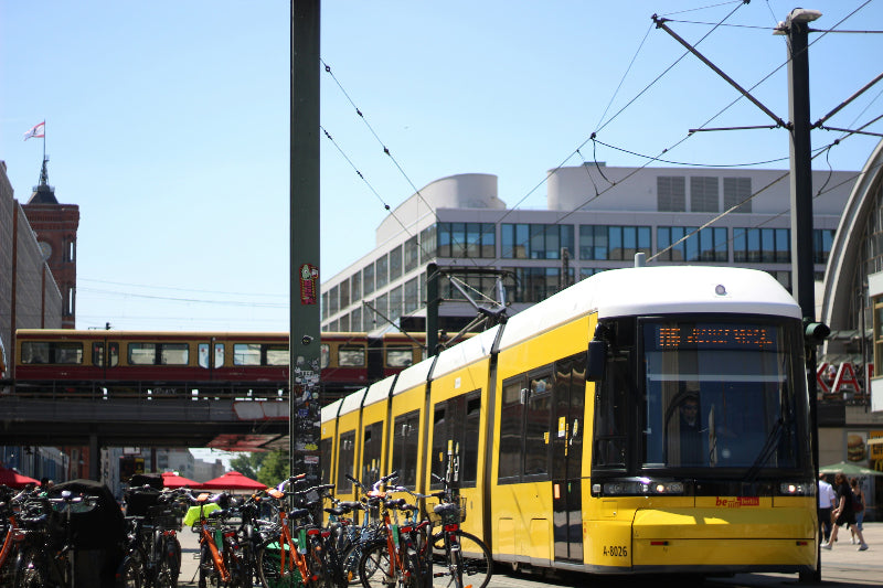 Einfahrende Straßenbahn in den Bahnhof Alexanderplatz mit rotem Rathaus im Hintergrund. 
