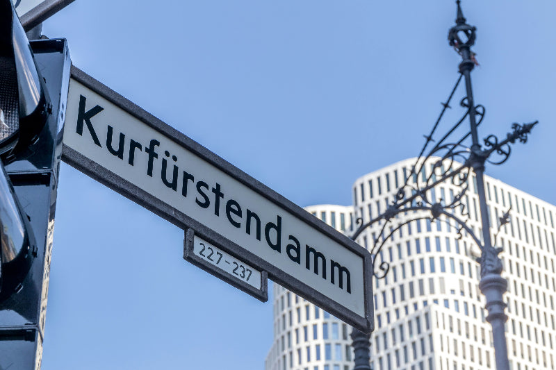 Straßenschild Kurfürstendamm und im Hintergrund das Stadtzentrum von West-Berlin. 