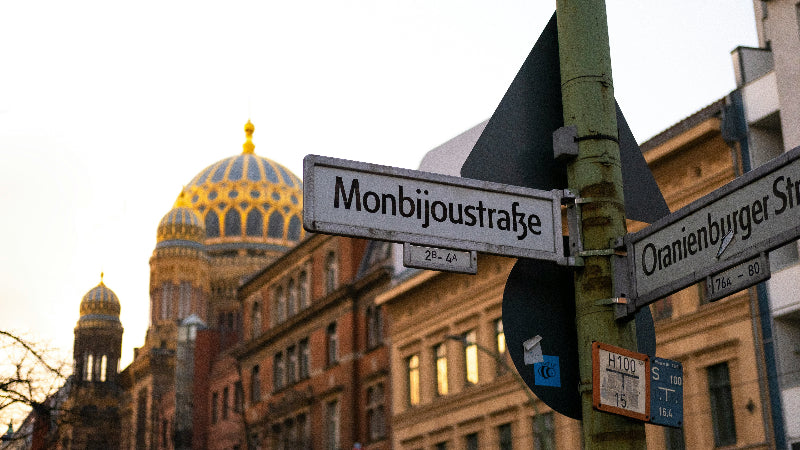 Foto vom Strassenschild "Monbijoustrasse" mit der jüdischen Synagoge im Hintergrund. 