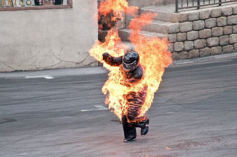 Stuntman mit Motorradhelm im Filmpark Babelsberg, welcher in Flammen steht.