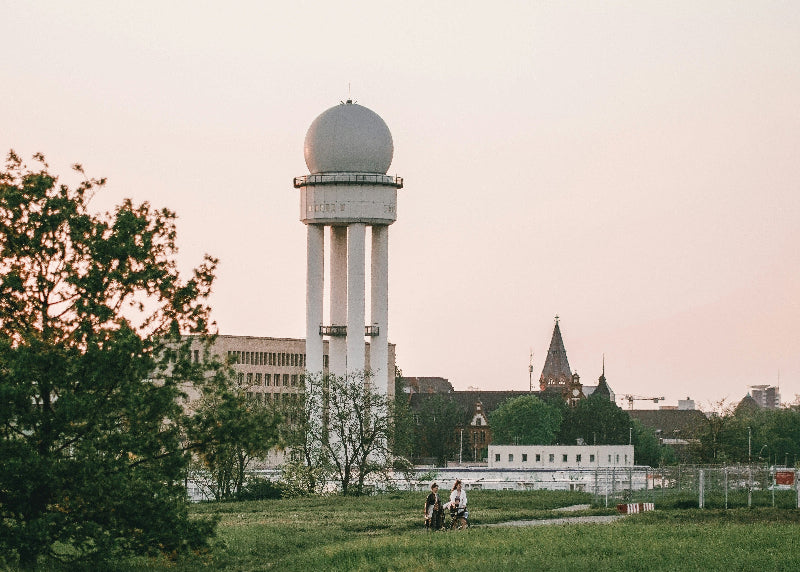 Weisser THF-Tower auf dem Tempelhofer Feld mit Fahrradfahrern im Vordergrund.