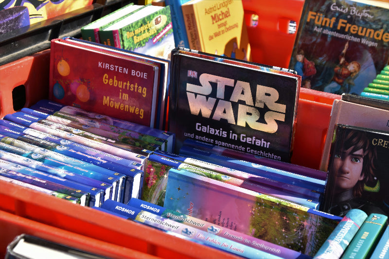 Kleine Kiste auf einem Flohmarkt-Stand mit Büchern und Spielen. 