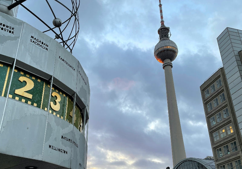 Foto der Weltzeituhr am Alexanderplatz mit dem Fernsehturm im Hintergrund. 