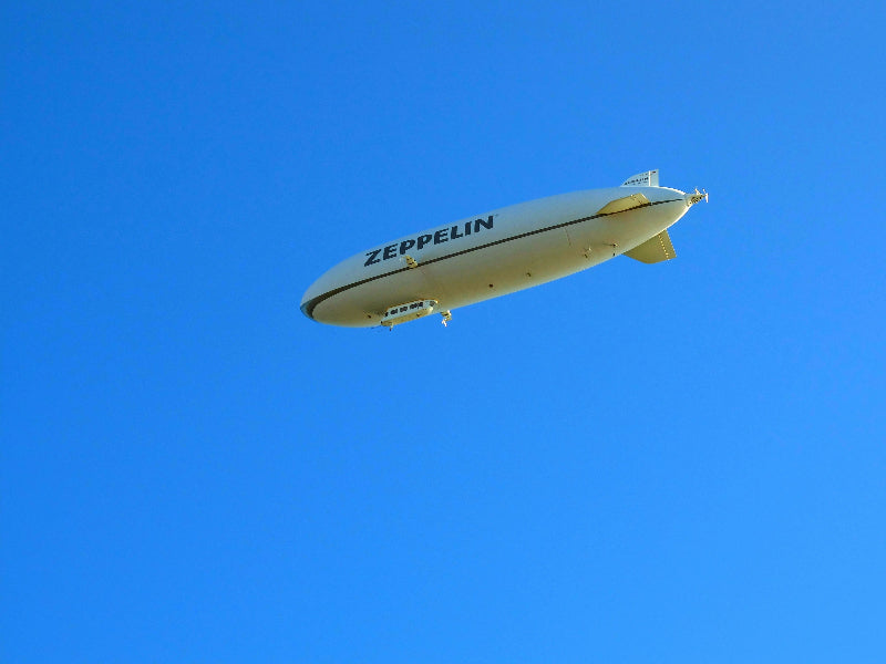 Foto eines Zeppelins mit der Aufschrift "ZEPPELIN" am blauen Himmel