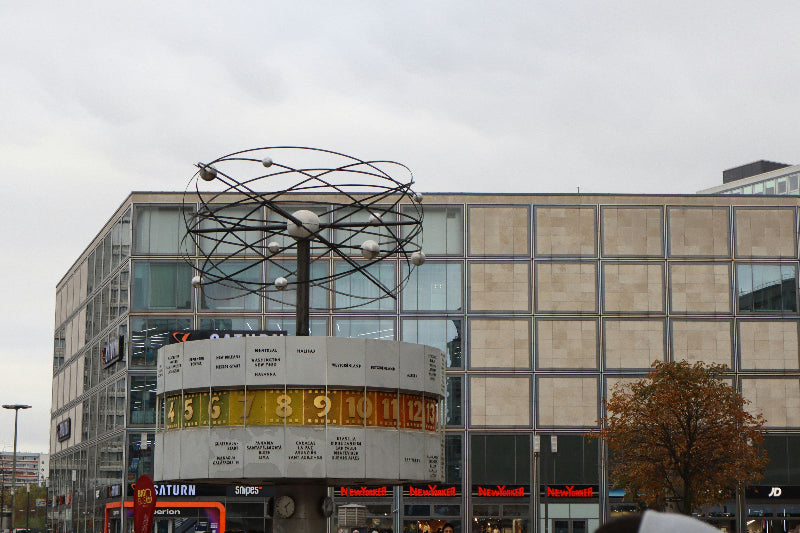 Foto der Weltzeituhr am Alexanderplatz mit einer großen Einkaufspassage im Hintergrund. 