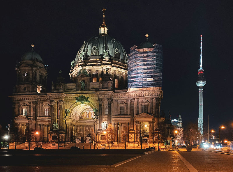 Foto vom Berliner Dom bei Nacht mit angestrahltem Fernsehturm. 