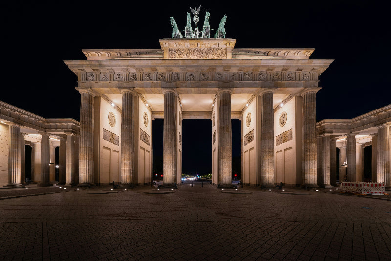 Foto vom beleuchteten Brandenburger Tor als Sehenswürdigkeit in Berlin bei Nacht.