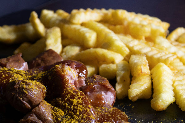 Foto von einer currywurst und Pommes in einem berliner Imbiss. 