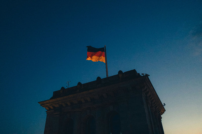 Deutschlandflagge auf dem Turm vom Reichstag in Berlin bei Dunkelheit. 