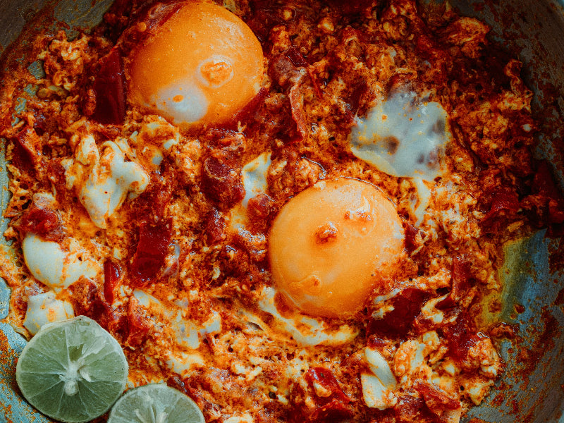 Foto von gebratenen Eiern in einem persischen Gericht mit Tomaten und Limetten. 