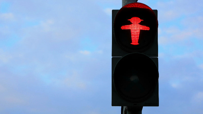Farbiges rot-leuchtendes Ampelmännchen auf einer Fußgängerampel in Berlin. 